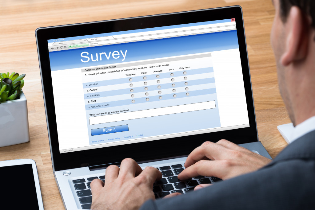 Cropped image of businessman giving online survey on laptop at office desk