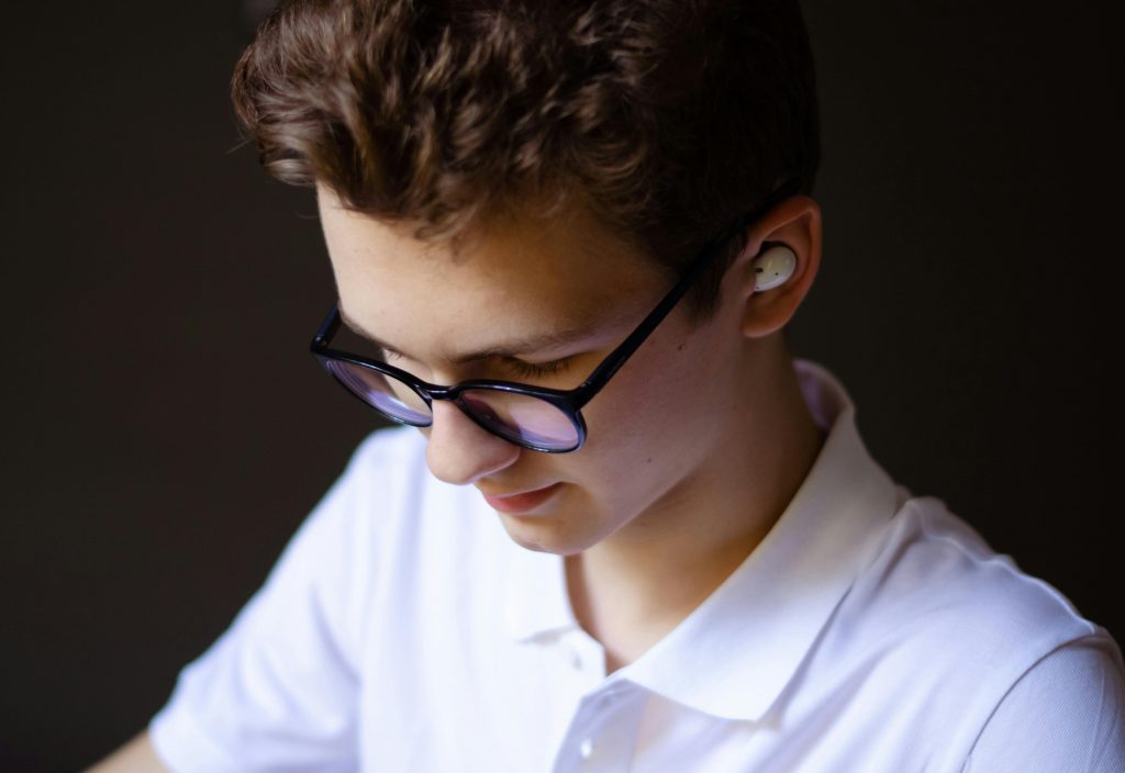 man with translation earbuds and eyeglasses looking down