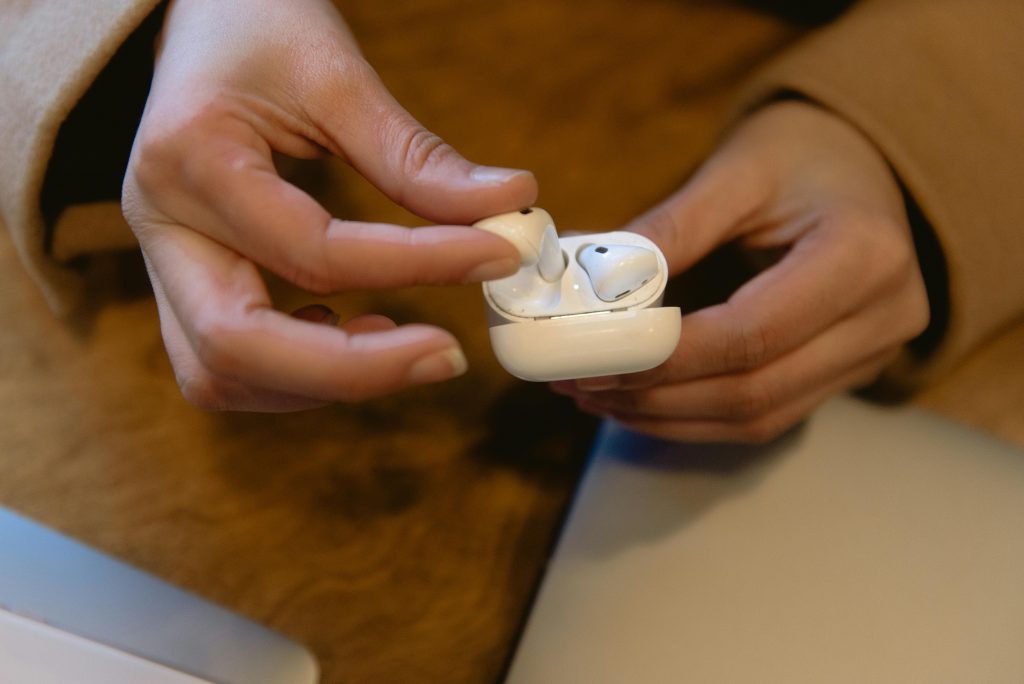 close-up of a person's hand removing a wireless earbud from its charging case
